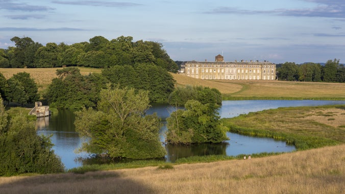View over the lake with surrounding trees towards the house at Petworth, West Sussex